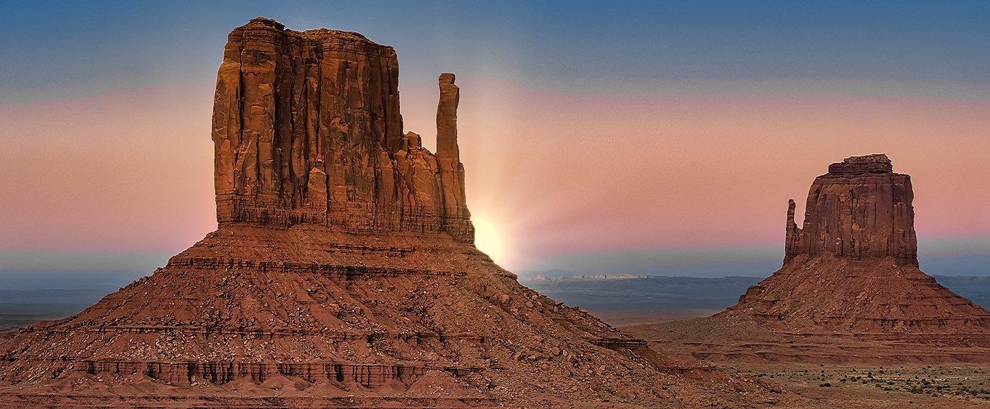Red sandstone towers rise above Monument Valley, on the Navajo Nation. The Thumb and Mittens are seen in the forefront.