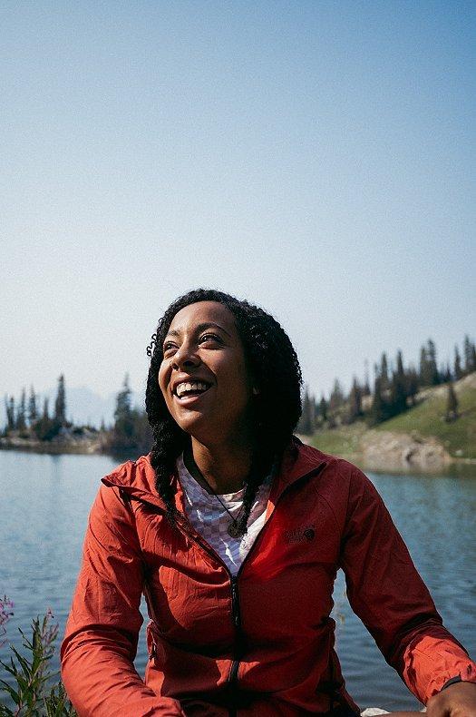 Genevive smiling up with an alpine lake in the background.
