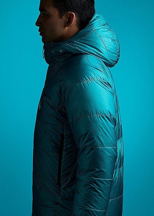 Side profile portrait in studio wearing theMen's Phantom™ Hoody with a tonal teal background to match the jacket