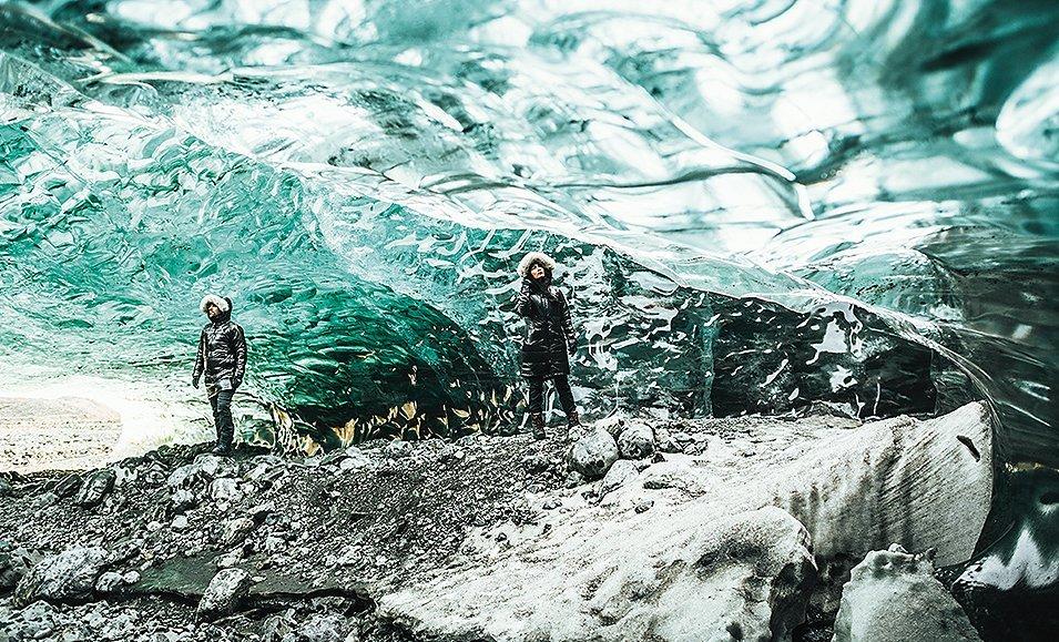 A man and woman exploring ice caves in Black Dot jackets.