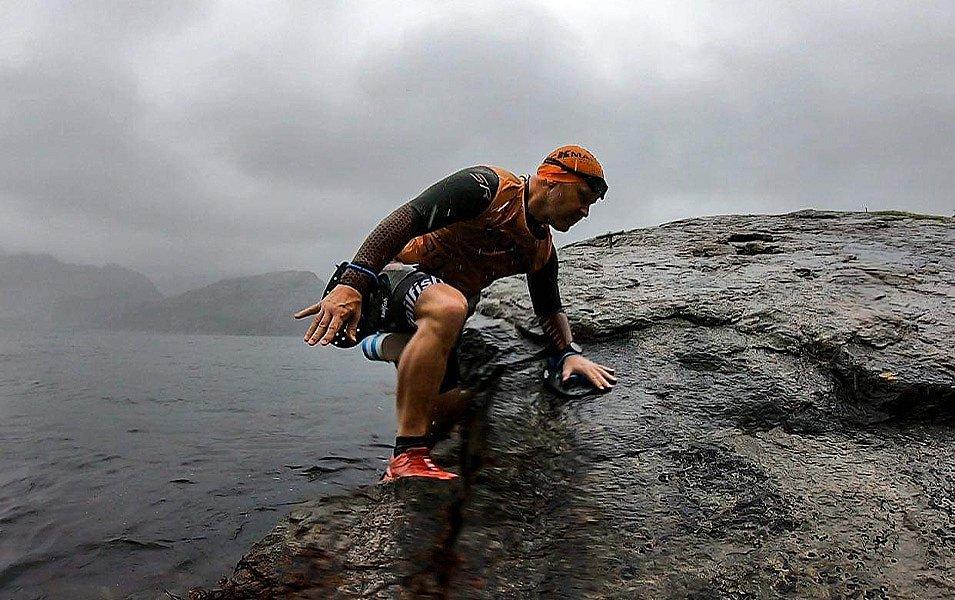 Thor Hesselberg exits the water wearing an orange top and swim cap during the Rockman Swimrun.