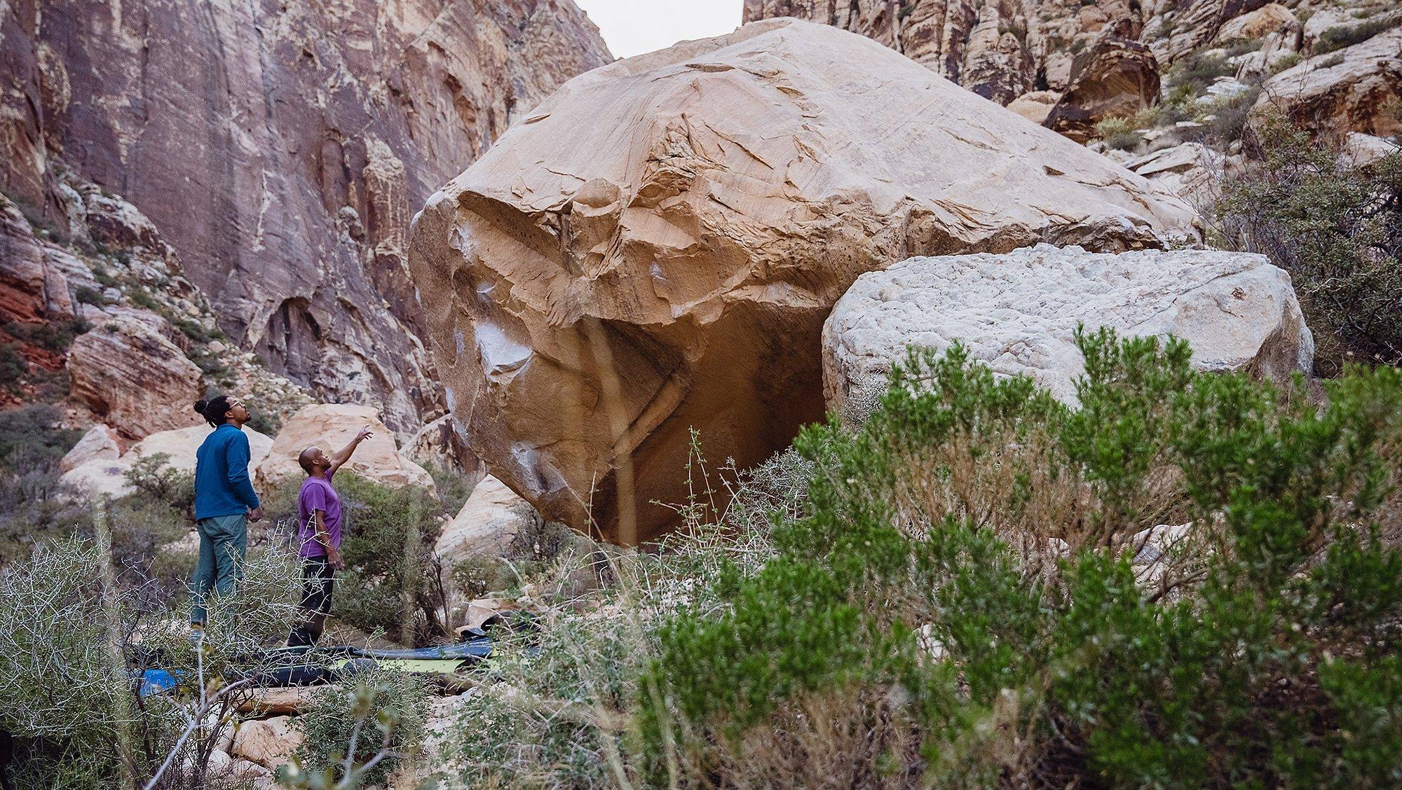 Caleb Robinson and Ayo Sopeju look at a bouldering problem together.