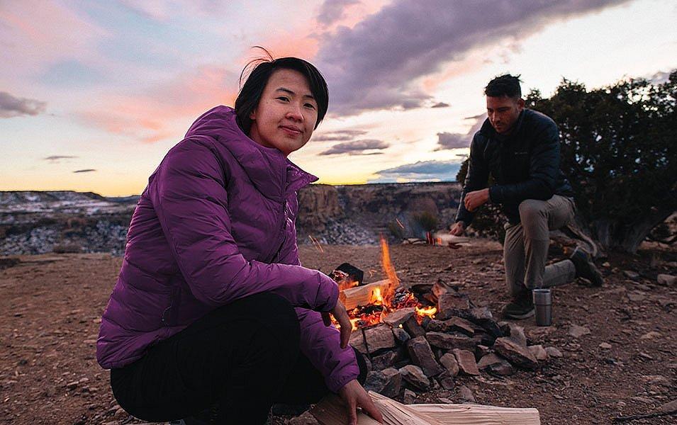 People besides a campfire at sunset. 