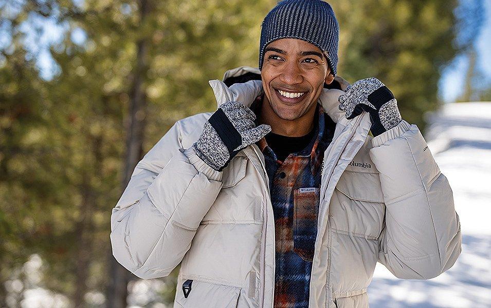 Man wearing a Columbia Puffy Jacket in a snowy forest. 