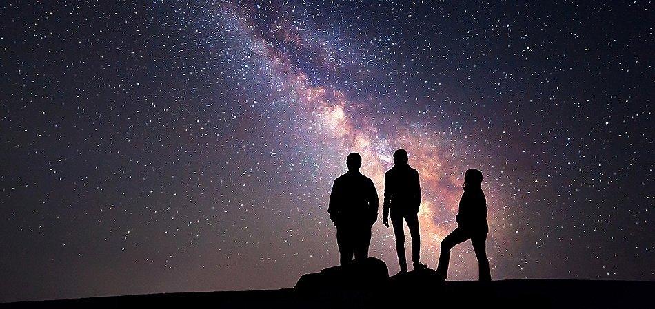 Three people silhouetted against the Milky Way.