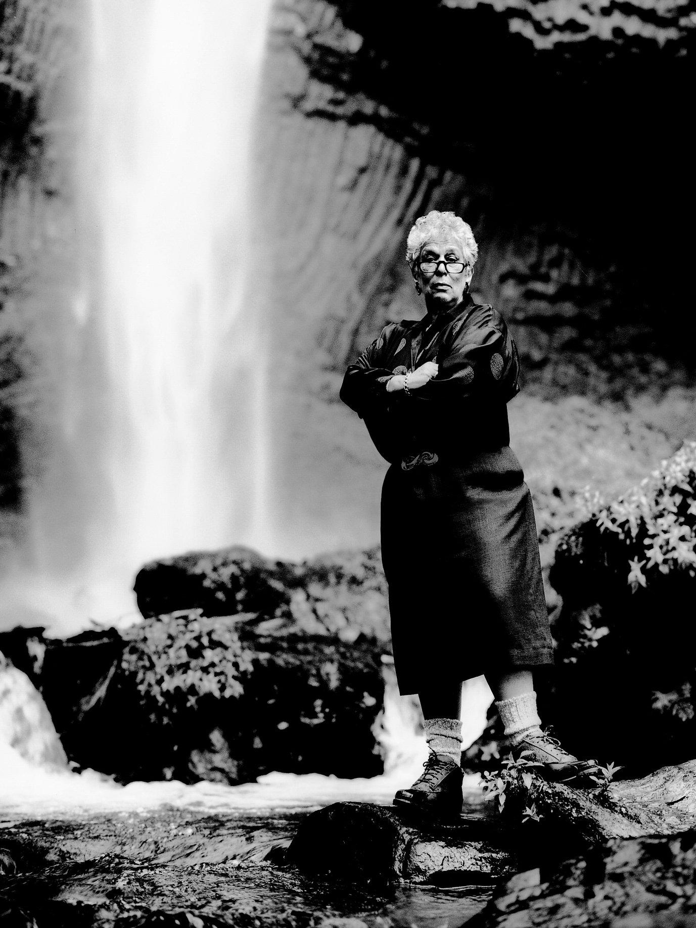 Gert Boyle standing in front of a waterfall.