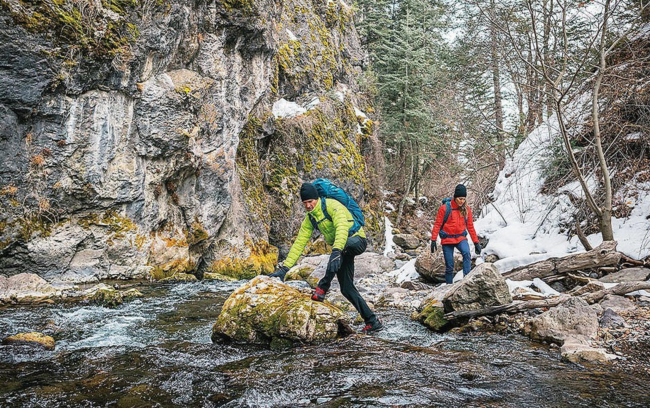 Two people crossing a river on a cold day.