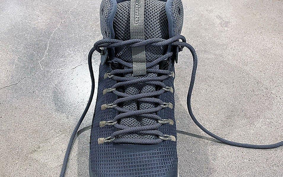A close-up shot of a blueish-gray Columbia Sportswear hiking boot displaying a surgeon’s knot in the laces.