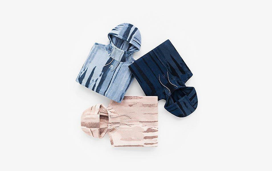 A man and a woman walk away from the camera in a scenic wooded area wearing Madhappy apparel. 