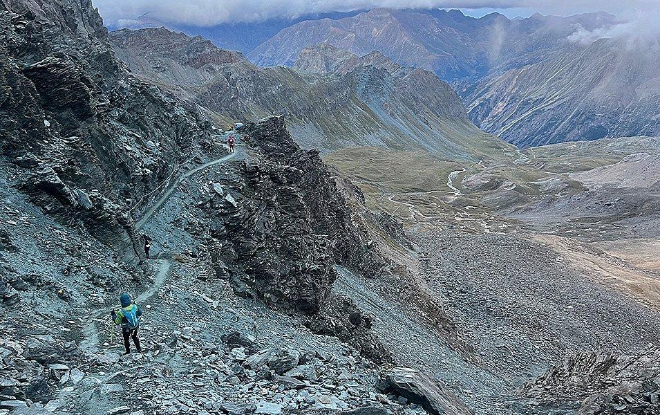 A long-distance runner in the 200-mile Tor des Géants race stands alongside the narrow rock strewn trail.
