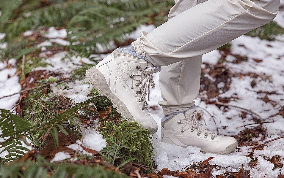A close-up shot of a pair of white Columbia Sportswear boots walking in a snowy setting. 