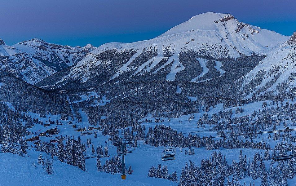 un chalet de ski enneigé et un télésiège avec une montagne en arrière-plan.