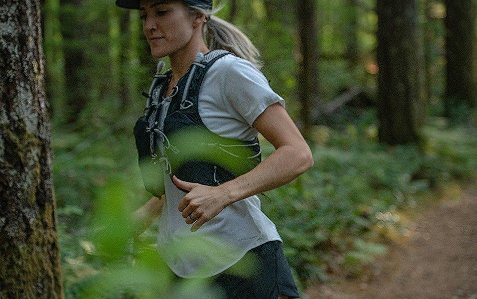 Woman running along a forested trail. 