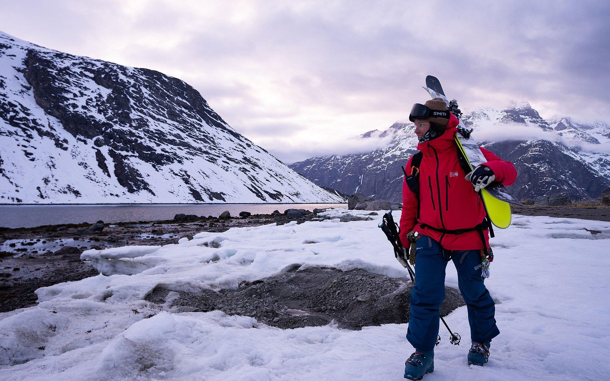 Rachael walking in Greenland, carrying skis from an outing.