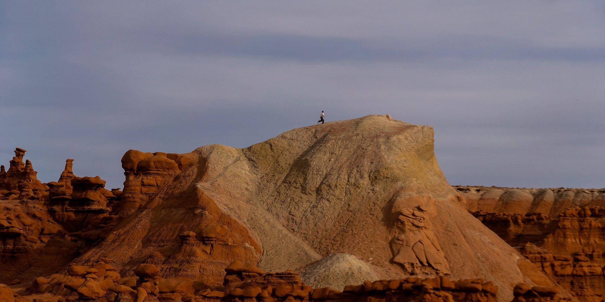 Hank in the distance on desert rocks in the southwest.
