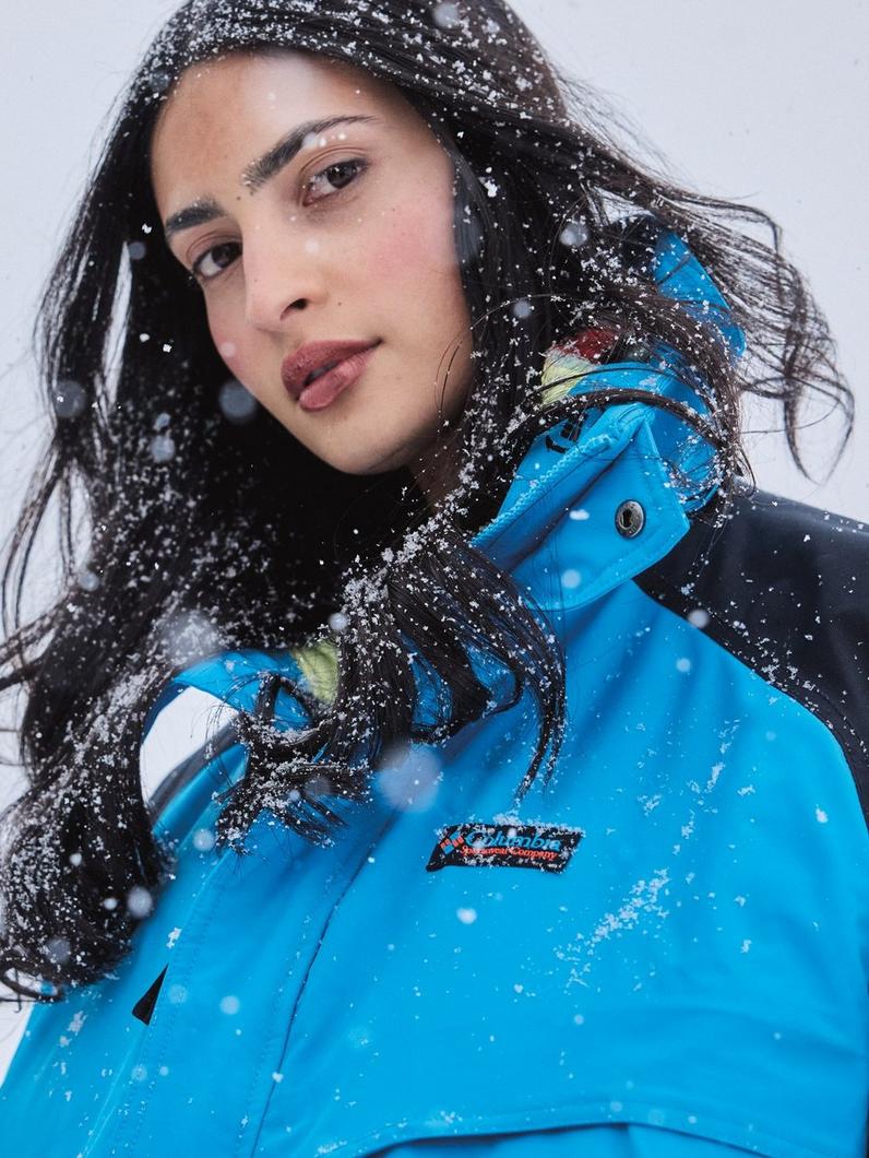 Portrait of a woman getting snowed on in a blue jacket.