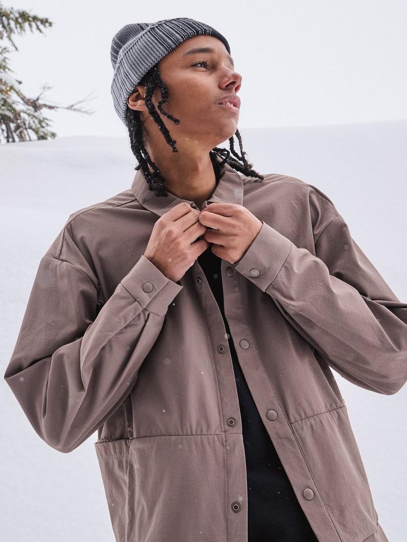 A young man in a button-up and beanie.