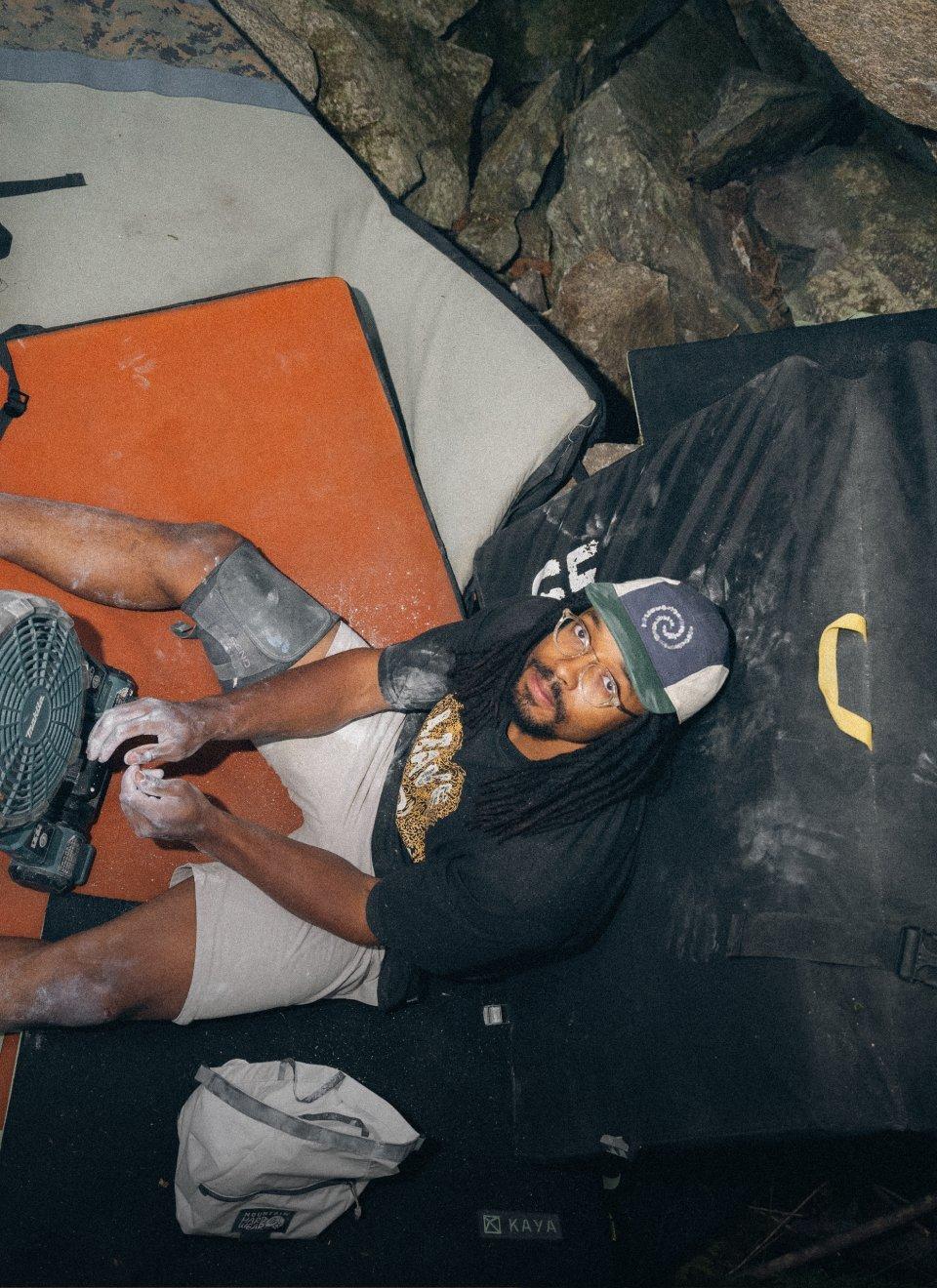 Caleb Robinson sitting on boulder crash pad.