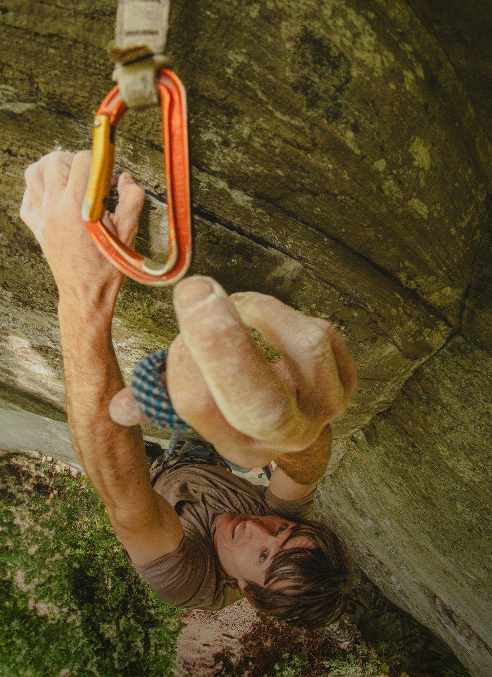 Ethan Pringle clipping in while climbing.
