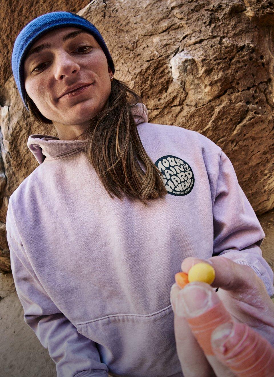 Kyra Condie chalked up at a rock wall and eating skittles.