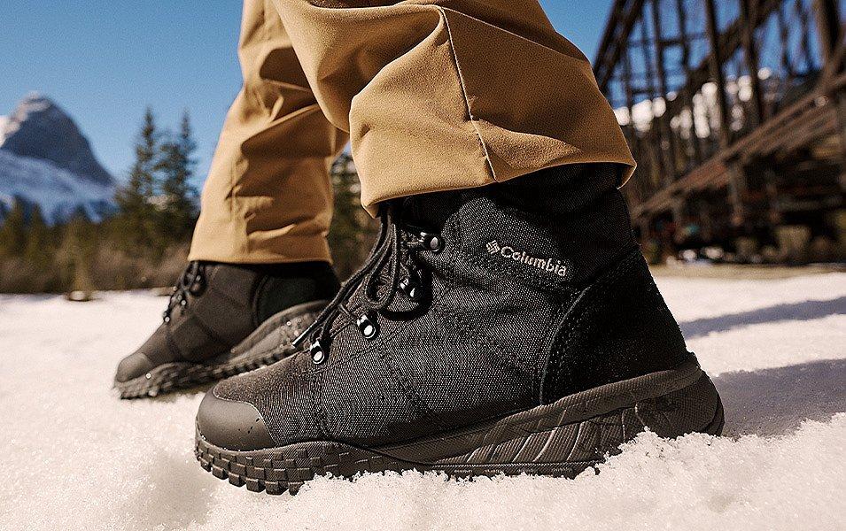 Close up of black Columbia Sportswear winter boots walking across a snowy meadow. 