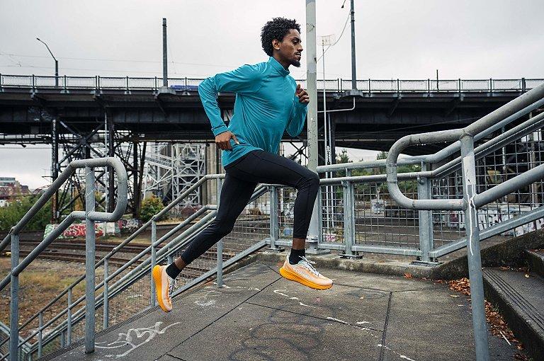 A man running up cement steps in an urban environment.
