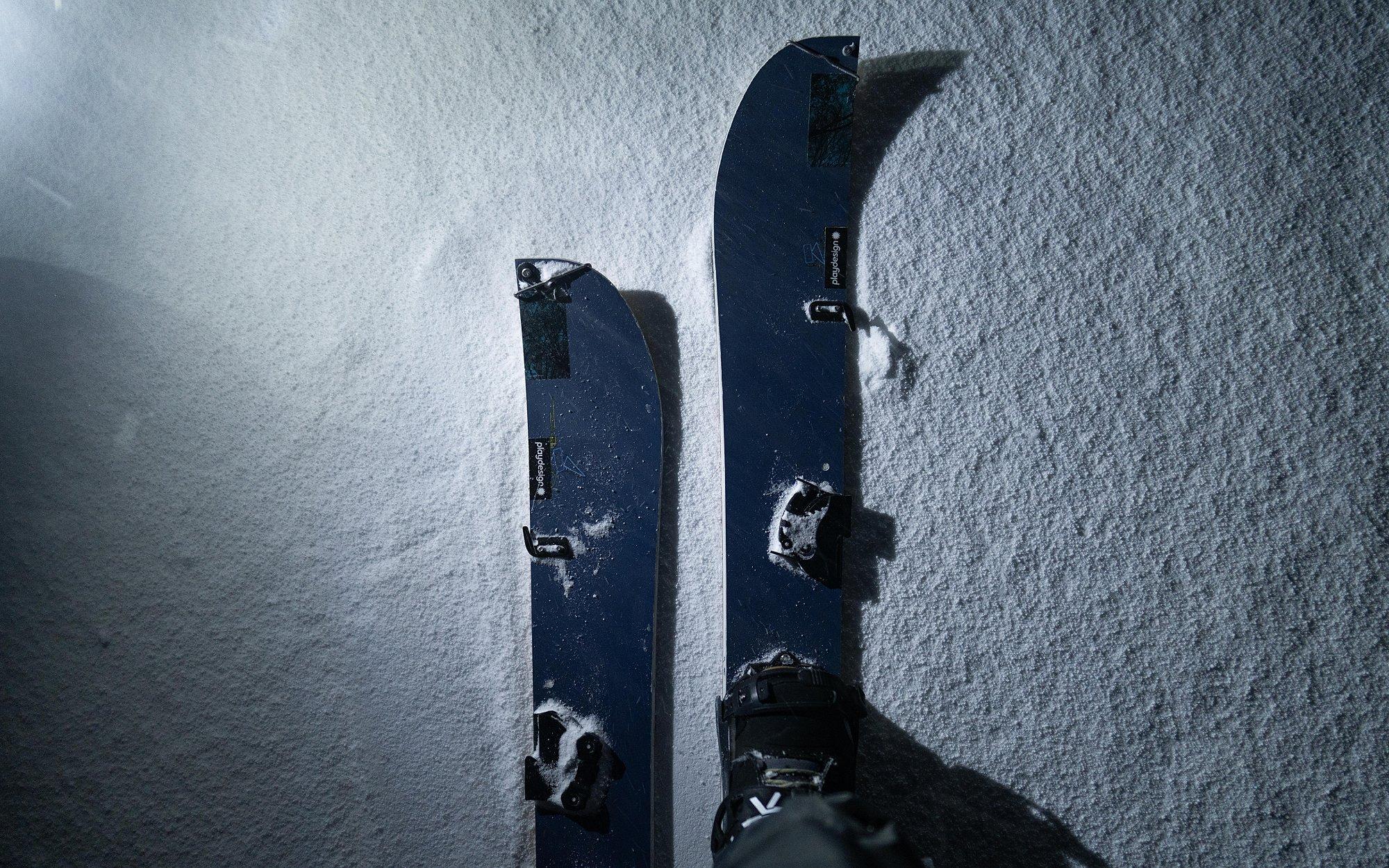 Looking down at one of their splitboards lit up by a headlamp.