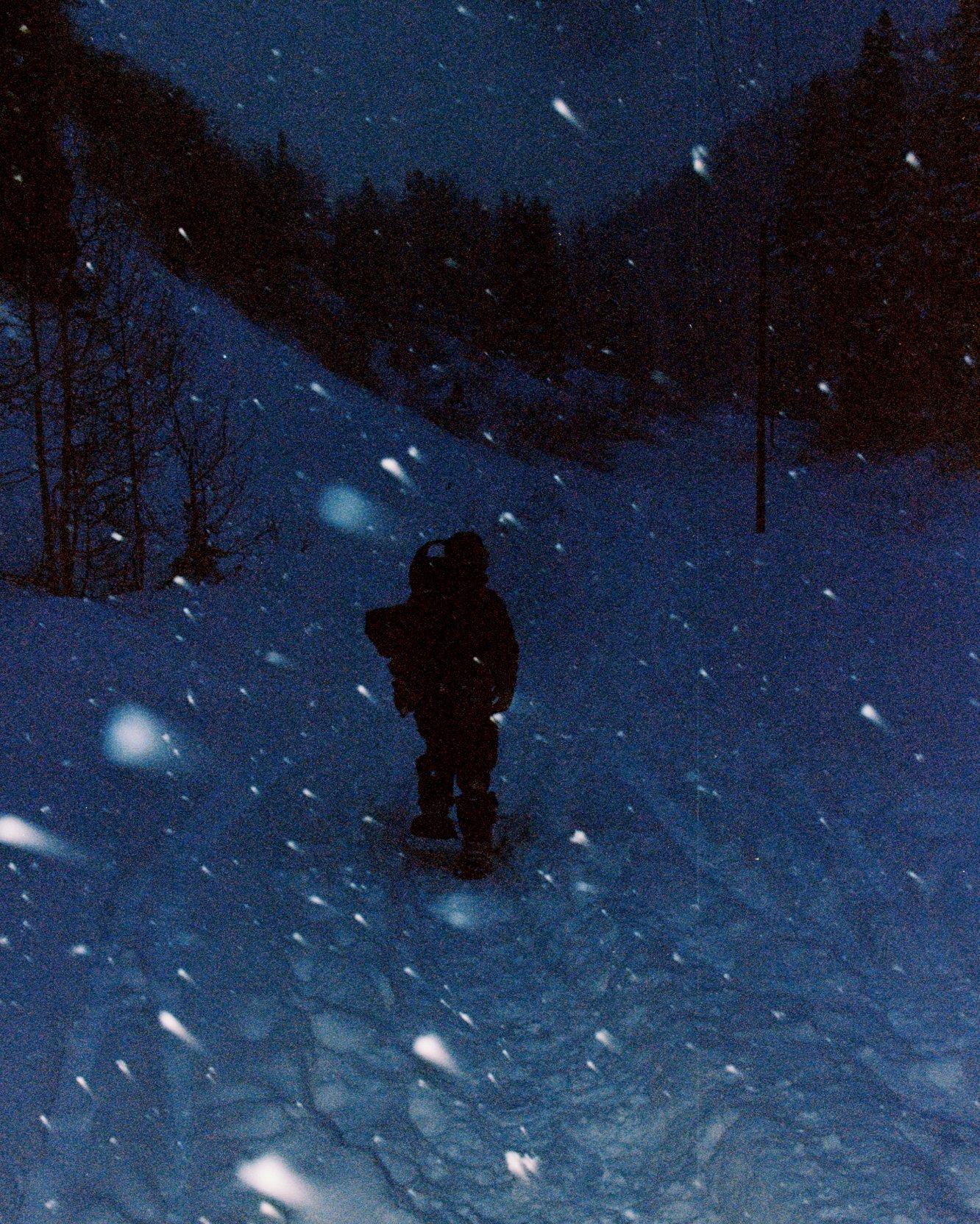 Skinning at dusk in snow flurries in a snow forest.