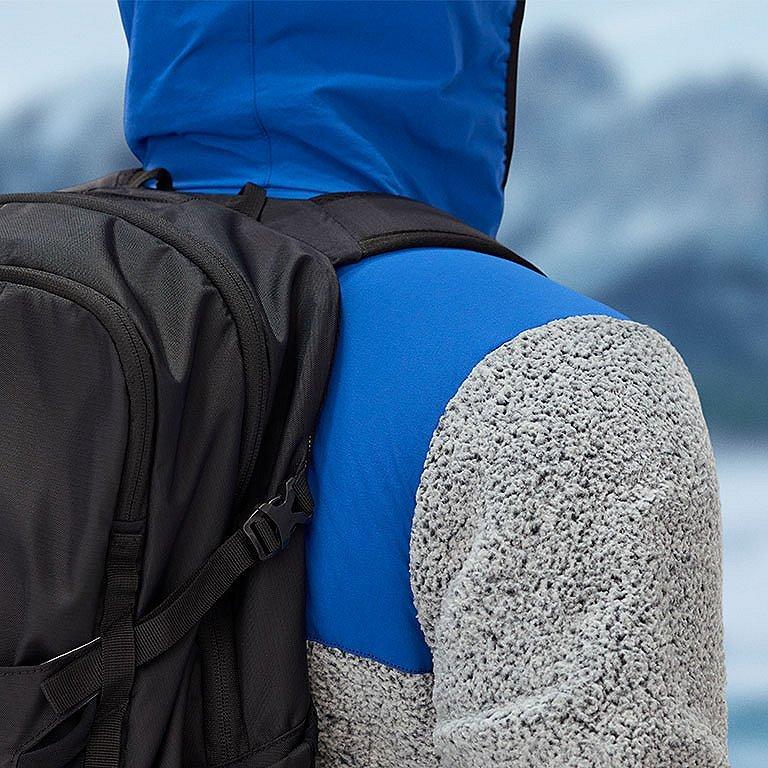 Model unzipping the bottom legs off of the tan convertible pants.