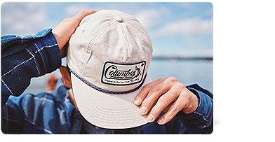 A man posing with a ball cap on.
