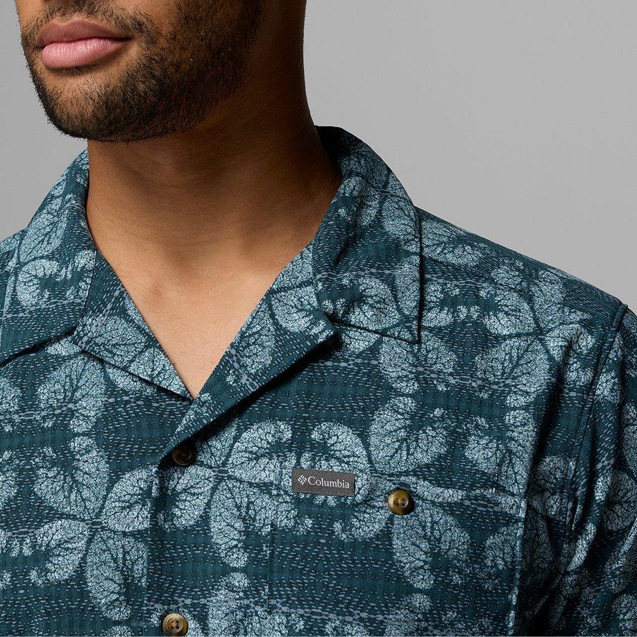 A man wearing a blue printed shirt with a collar.