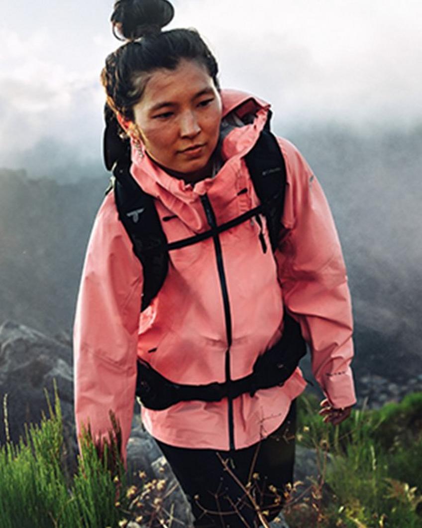 Women hiking in a salmon colored raincoat.