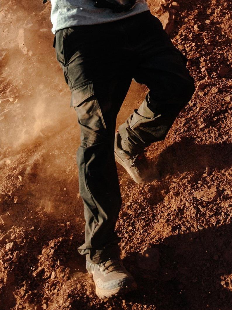 Someone scaling down a steep gravely hill in slacks.