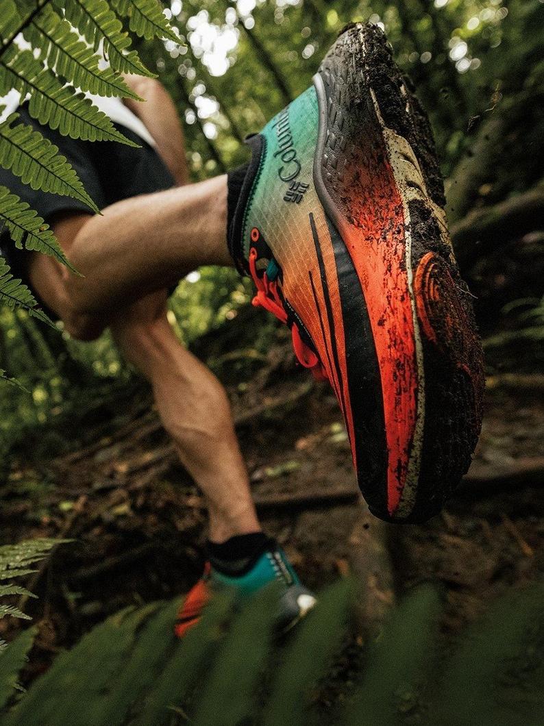 Close-up of a person's red and teal running shoe as they tear through a forest.