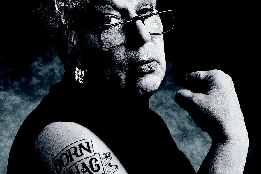 Black and white photo from the nineteen eighties Gert Boyle flexing with a "born to nag" tattoo on her arm.
