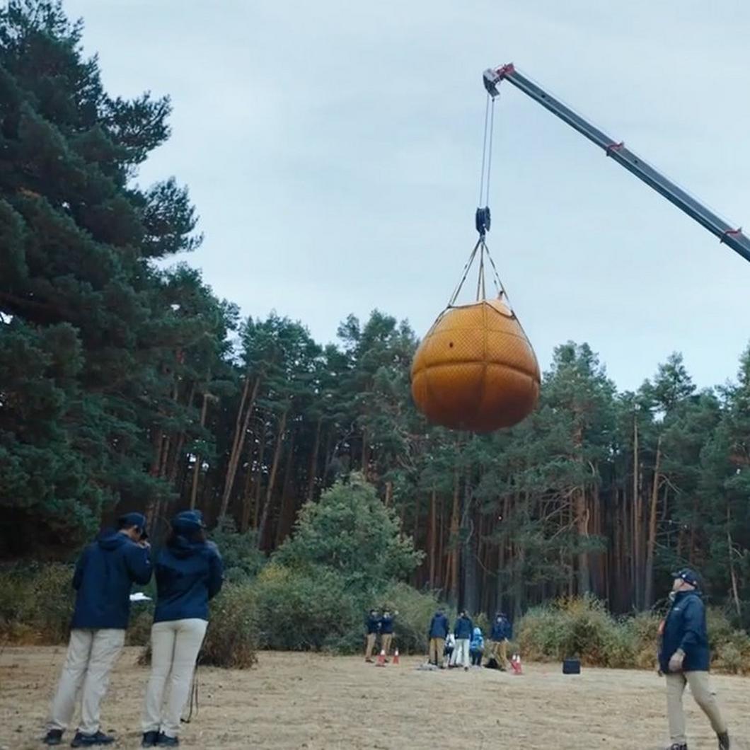Thumbnail of gallons of water about to be dropped on two people in waterproof gear.