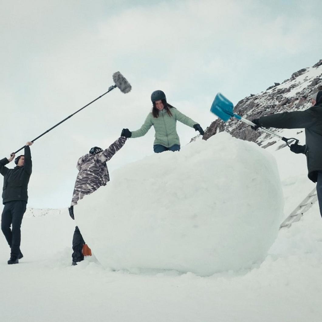 A team of stunt people setting up a stunt woman inside of a giant snowball.