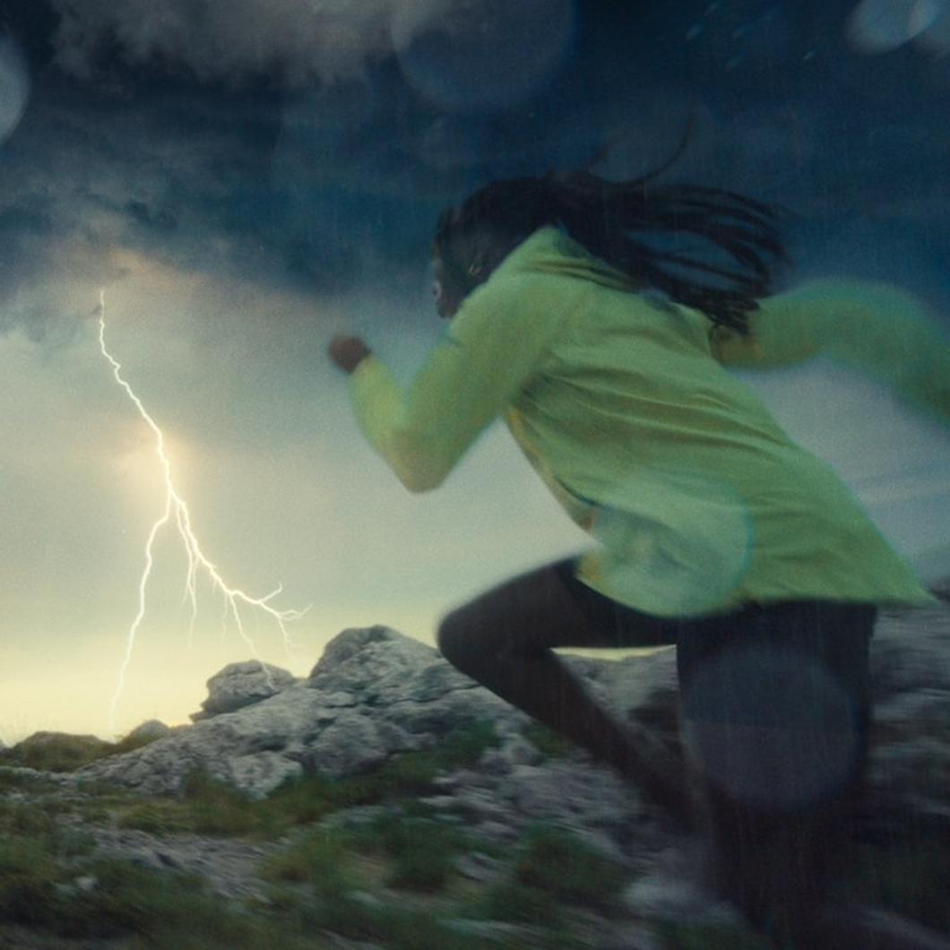 A woman running in a lighting storm.