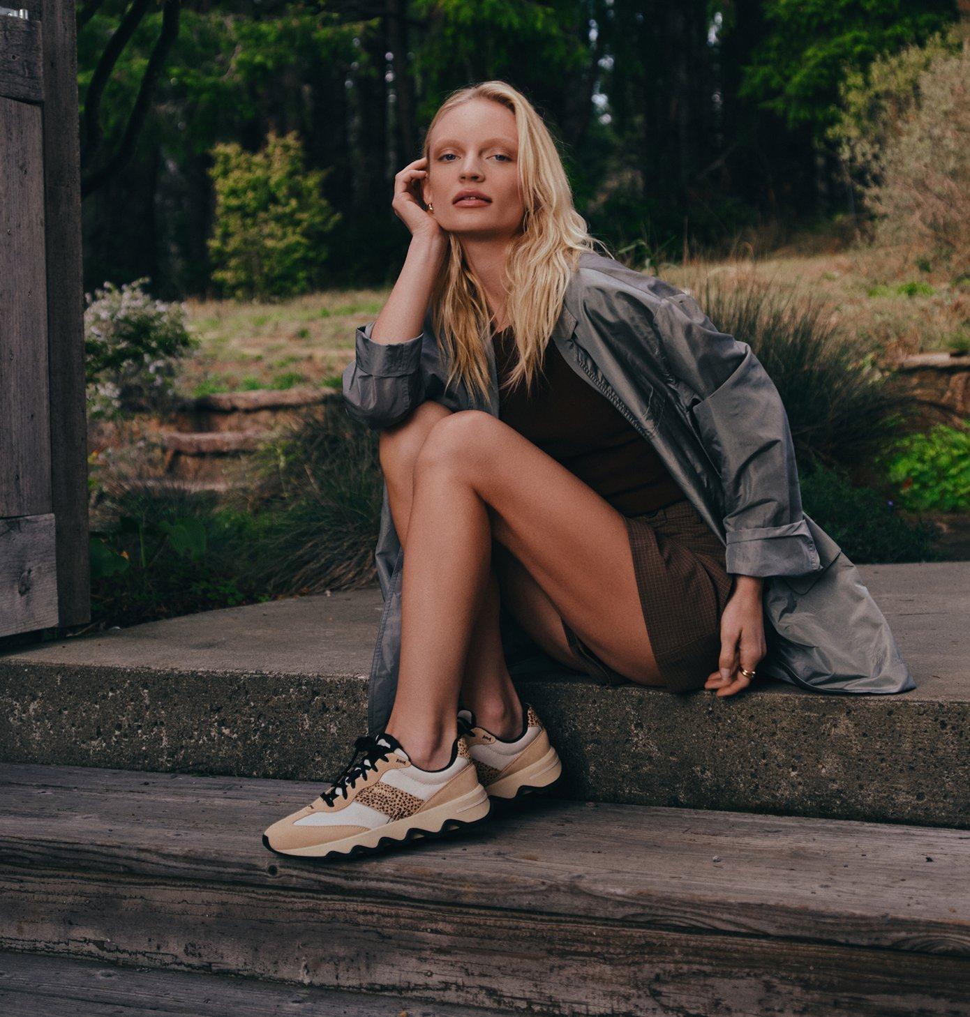 woman sitting on steps wearing kinetic ember sneakers 