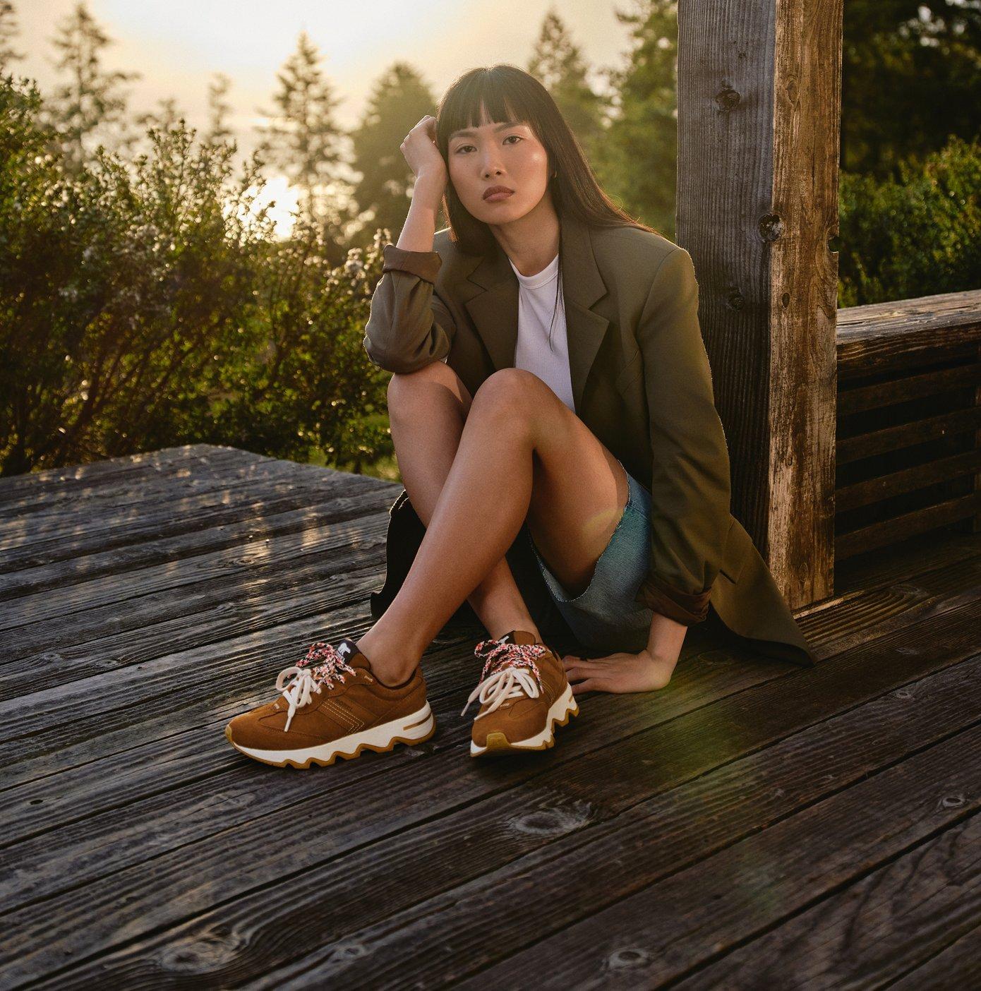 woman sitting on a dock wearing kinetic ember lx sneakers