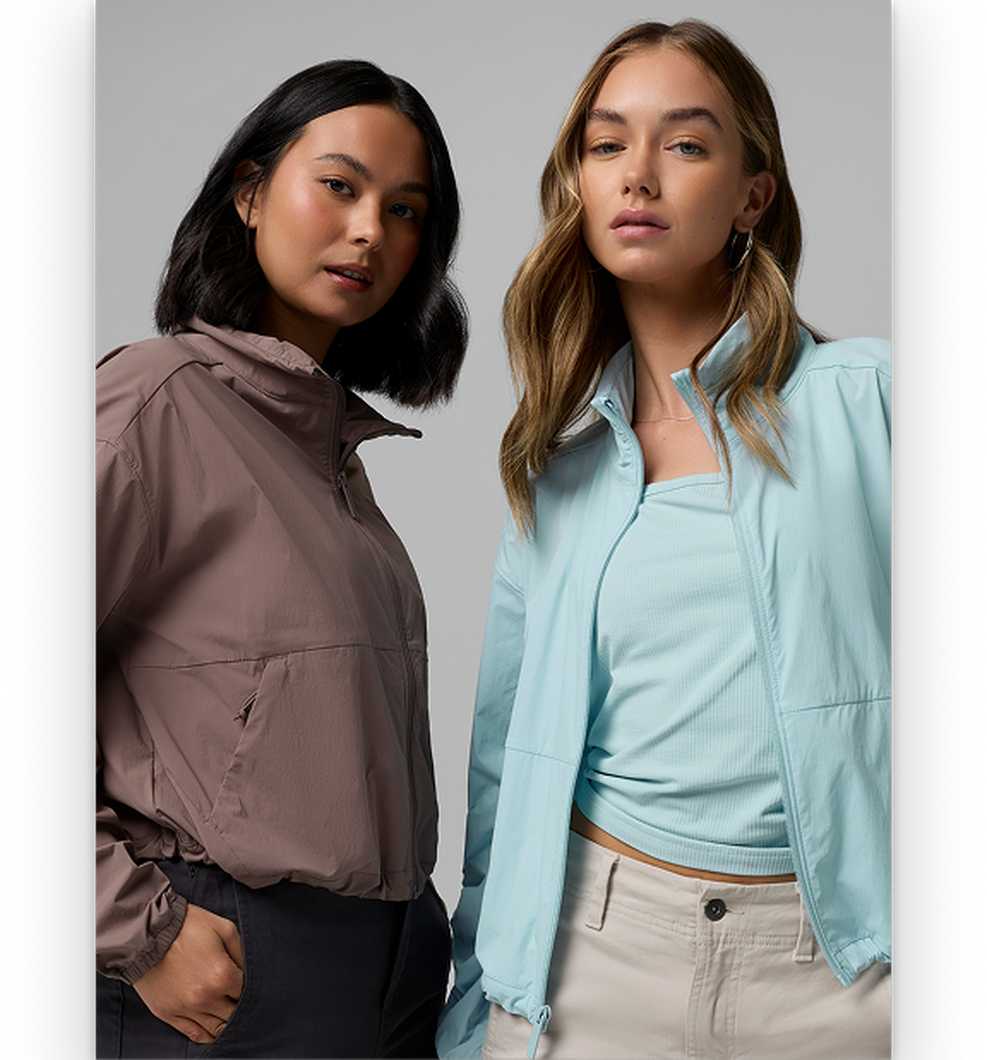 Two women modeling zip-up jackets, one in taupe and one in light blue, paired with casual bottoms.