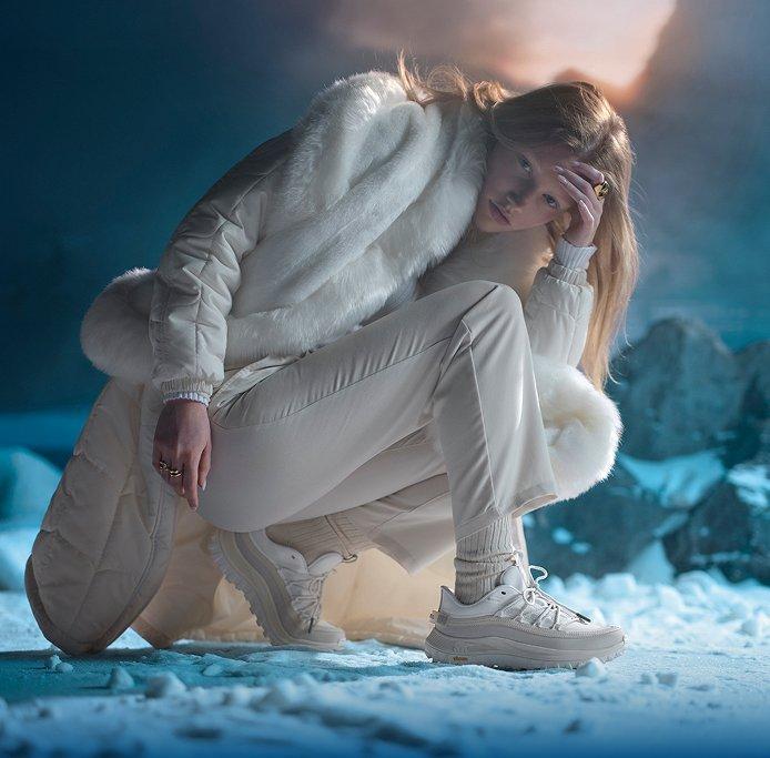 sorel woman kneeling in white callsign sneakers