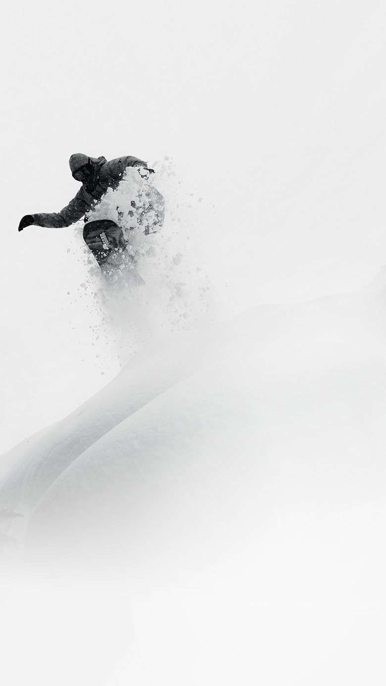 A snowboarder making a big on a snowy hill