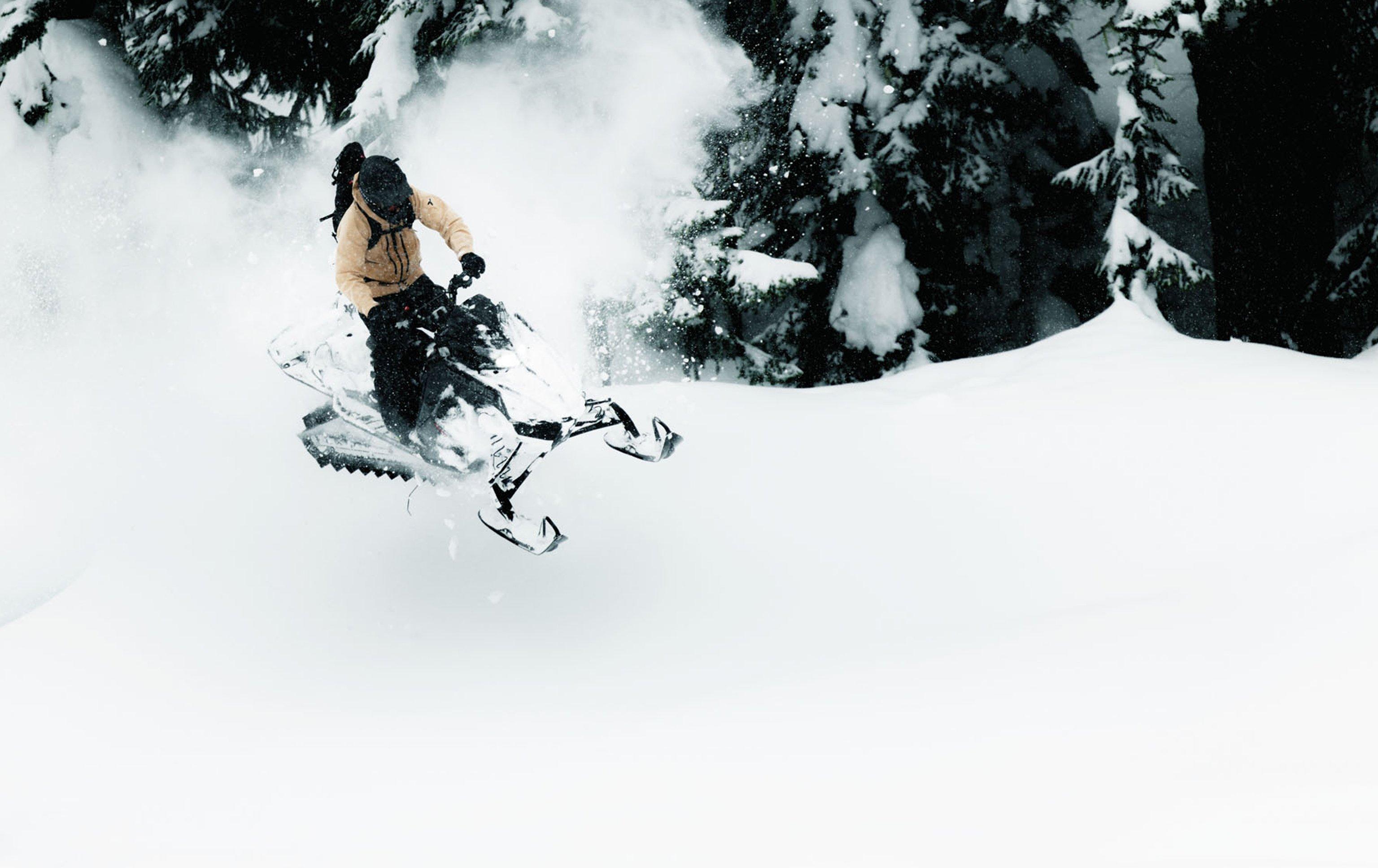 A snowmobiler speeding through fresh powdery snow.