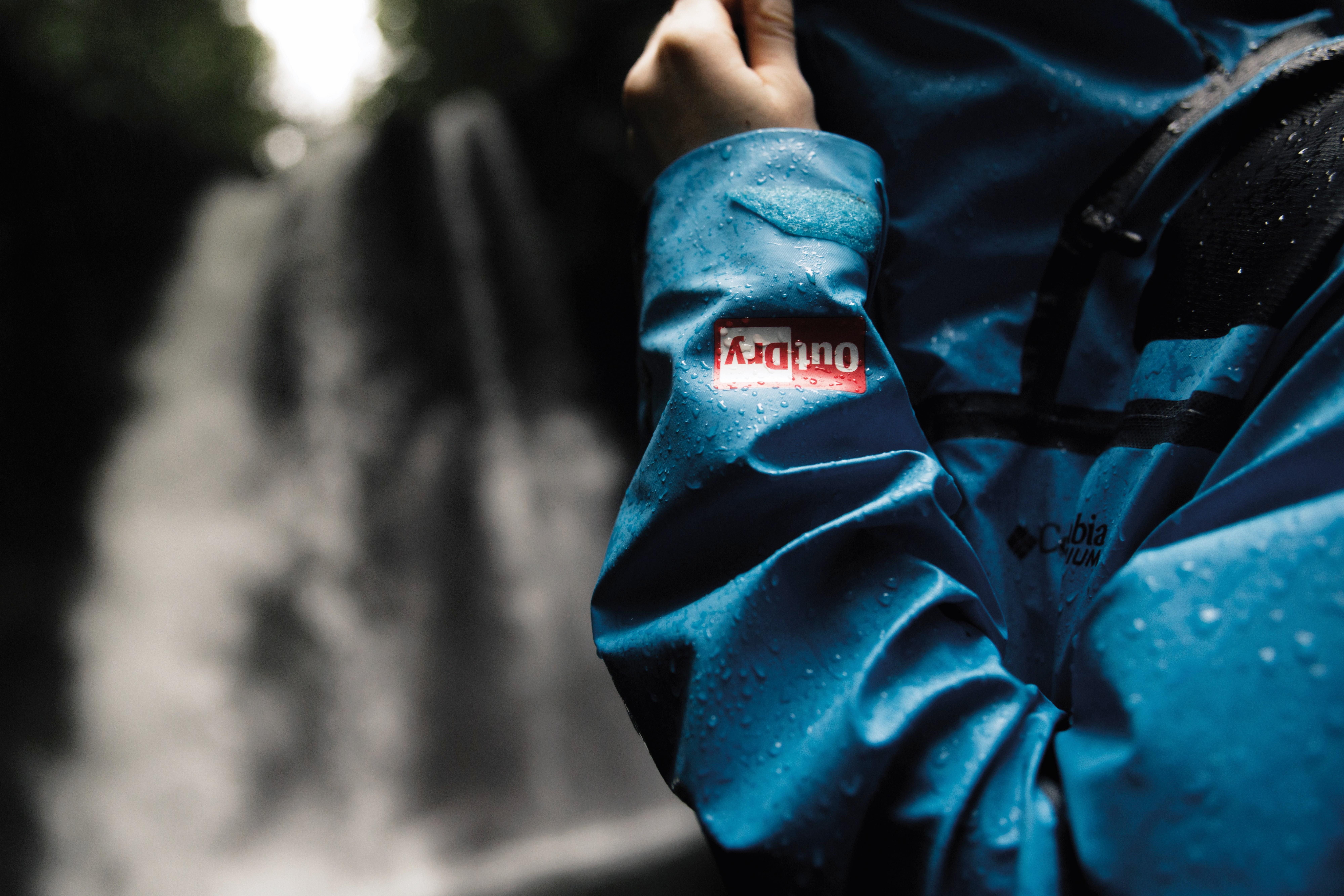 Close-up of a person's green rain jacket with the Titanium logo on the sleeve.