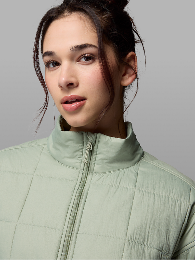 A woman wearing a light green insulated jacket.