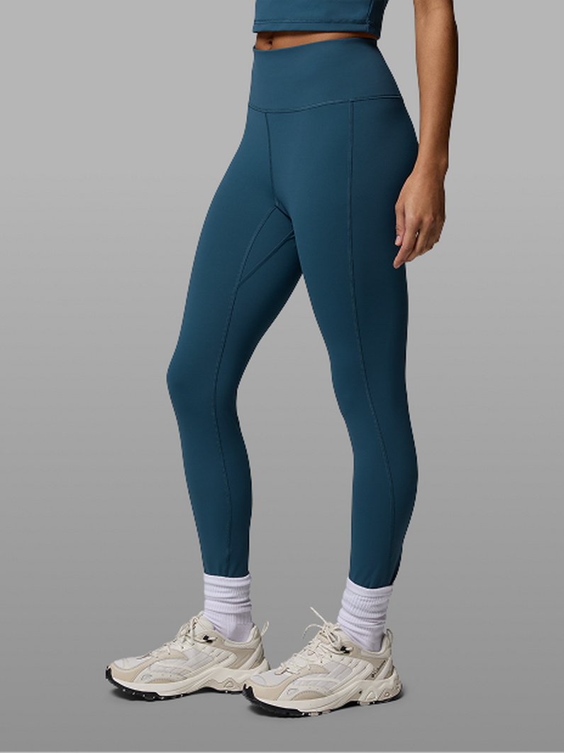 Waist-down image of a woman wearing blue leggings and sneakers.
