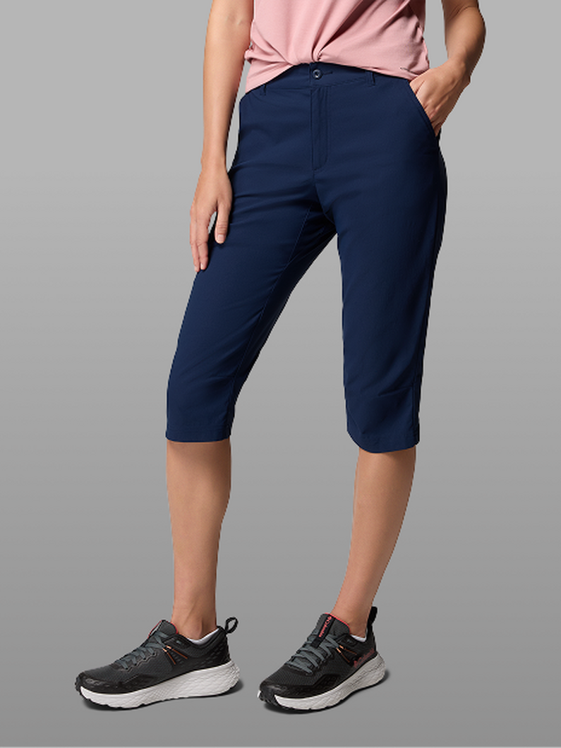 Waist-down image of a woman wearing navy capris and sneakers.