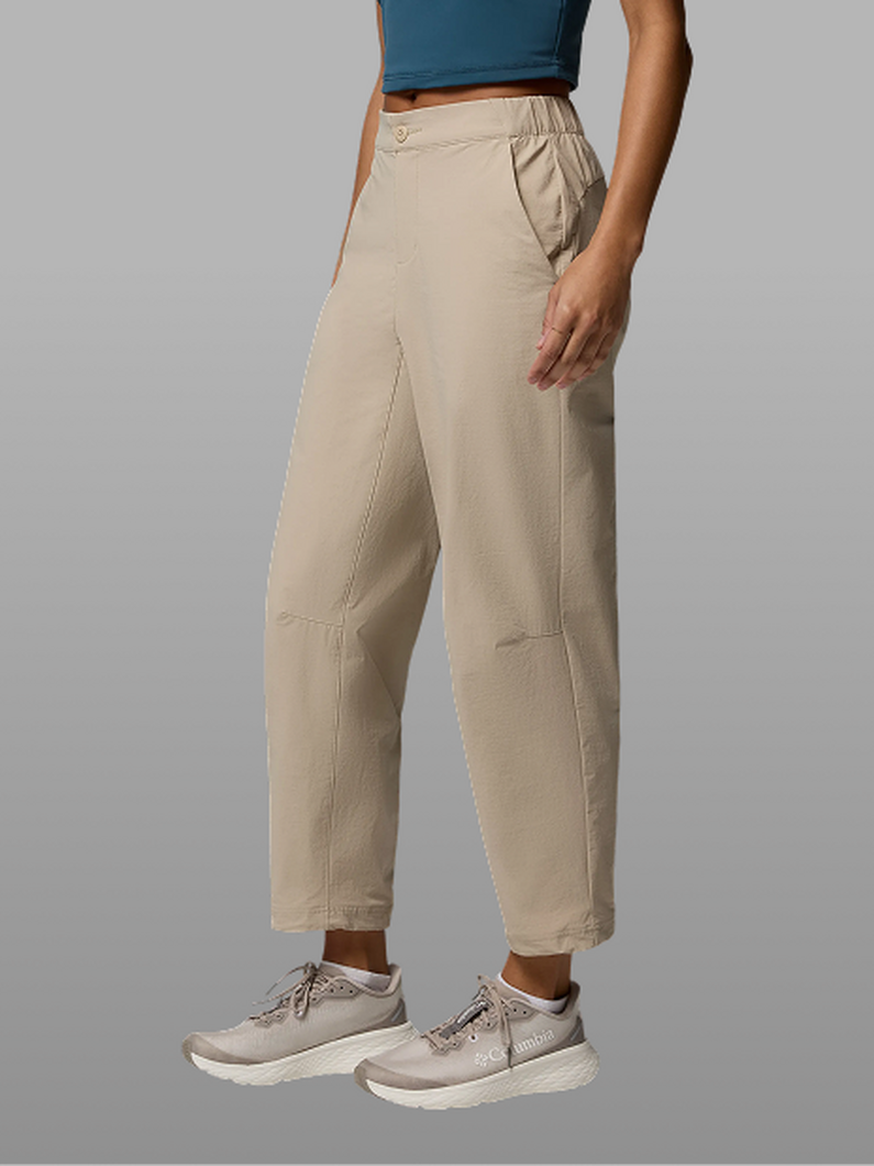 Waist-down image of a woman wearing tan pants and sneakers.