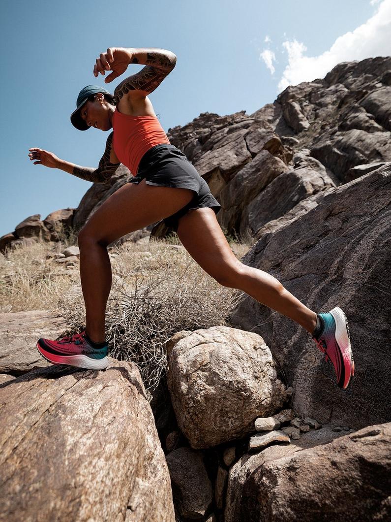 Action shot of model running up rocky terrain in Konos trail shoes.